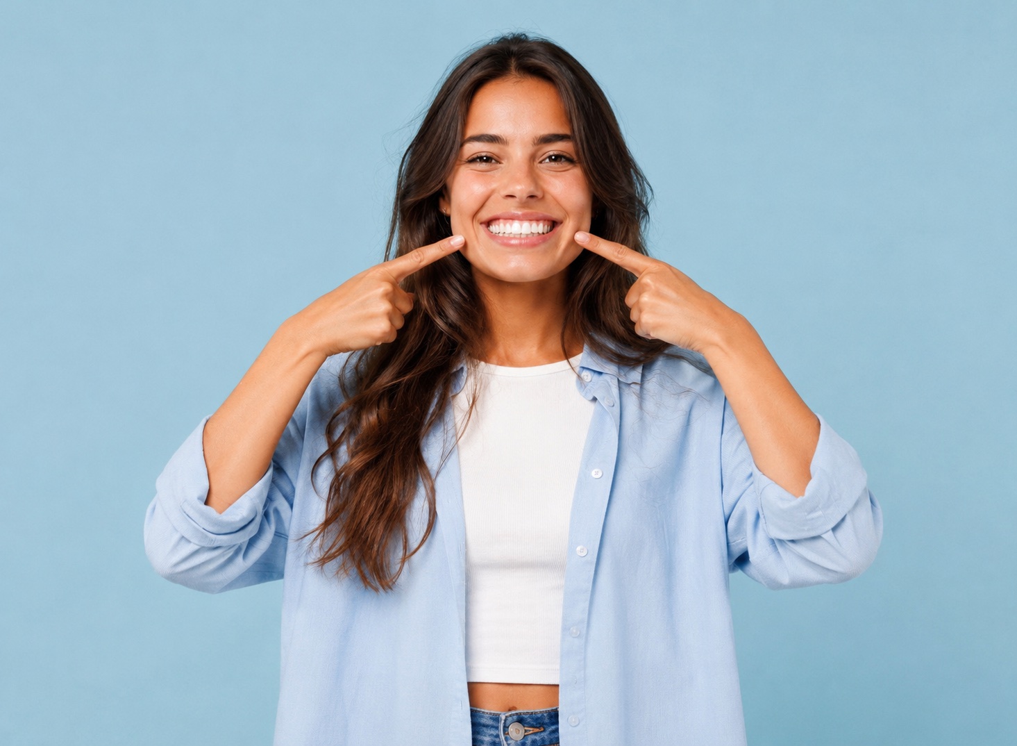 Jeune femme souriante montrant son sourire du bout des doigts